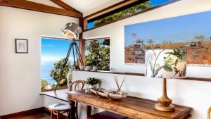 a dining room with a table and two windows at Atlas Beach House in Killcare