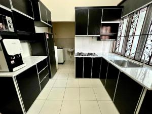 una pequeña cocina con armarios negros y fregadero en Rumah Mok Aji Homestay Melaka en Melaka