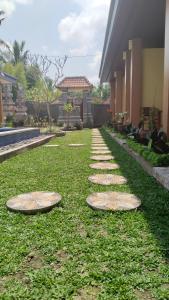 D'Natha Villa Ubud في أوبود: حديقة فيها طلعات على العشب