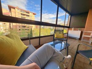 a person sitting on a couch in a room with windows at Dos Torres Gómez Laguna - Estacionamiento Privado Gratuito in Zaragoza