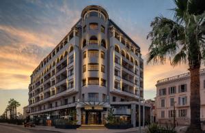 a tall white building with a palm tree in front of it at Canopy by Hilton Cannes in Cannes