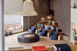 a living room with blue chairs and a spiral staircase at Vienna House by Wyndham MQ Kronberg in Kronberg im Taunus +115 photos