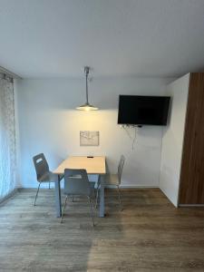 a dining room with a table and chairs and a flat screen tv at Beautiful Cozy Studio Davos in Davos