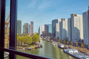 Blick auf einen Fluss mit Booten in einer Stadt in der Unterkunft Mainport Hotel Rotterdam, a Hilton Affiliate Hotel in Rotterdam
