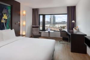 a hotel room with a bed and a desk and a window at Maashotel Rotterdam Centre in Rotterdam