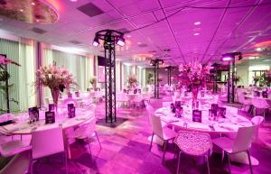 een feestzaal met witte tafels en stoelen en paarse verlichting bij Mainport Hotel Rotterdam in Rotterdam
