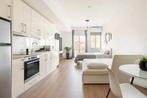 uma cozinha e sala de estar com armários brancos e uma mesa em Boutique Studios near Airport em Pallíni