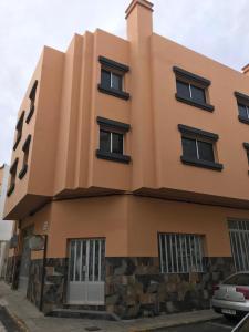 un edificio arancione con finestre nere su una strada di Apartamento Ilusión a Corralejo