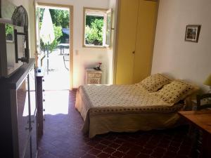 1 dormitorio con 1 cama y puerta que da a un patio en Les Oliviers, en Grimaud