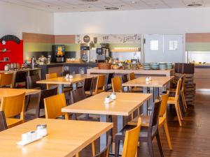 an empty restaurant with wooden tables and chairs at B&B Hotel Aachen-Hbf in Aachen