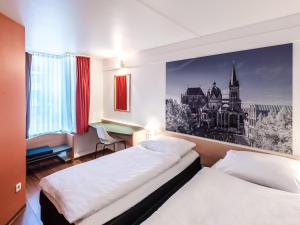 a hotel room with two beds and a desk at B&B Hotel Aachen-Hbf in Aachen