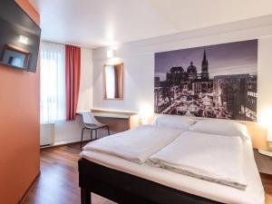 a bedroom with a bed with a picture on the wall at B&B Hotel Aachen-Hbf in Aachen