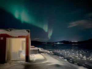 a building with a window in the snow with the northern lights at Norwegian Wild in Vangsvik