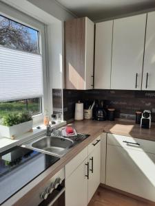 a kitchen with white cabinets and a sink and a window at Träumeria in Butjadingen