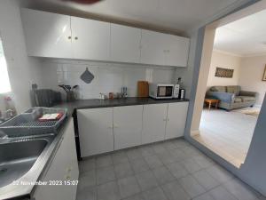 una cocina con armarios blancos y fregadero en Field's Rest, en Port Elizabeth