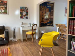a living room with a table and a yellow chair at Ejoki in Sarlat-la-Can&eacute;da