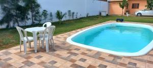 a table and chairs next to a swimming pool at Chácara Corujá in Juazeiro do Norte
