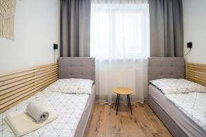 a room with two beds and a table and a window at Apartmany ROSTER in Liptovský Mikuláš