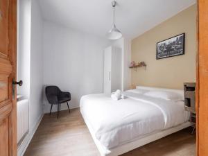 ein Schlafzimmer mit einem großen weißen Bett und einem Stuhl in der Unterkunft 6 Rue de Zurich - T3 avec grande terrasse in Straßburg