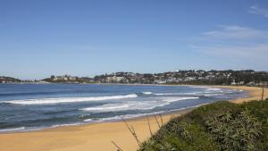 a beach with the ocean and waves at Surfers Corner on Wamberal Beach in Wamberal