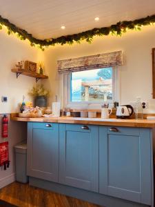 a kitchen with blue cabinets and a window at The original Sleeping Giant Lodge - Farm Stay, meet the animals in Ystradgynlais