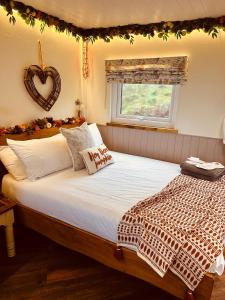 um quarto com uma cama grande com um sinal de coração na parede em The original Sleeping Giant Lodge - Farm Stay, meet the animals em Ystradgynlais