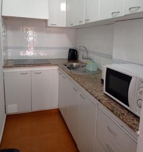 cocina blanca con microondas y fregadero en Casa en la playa, Aldea Coast, en San Nicolás
