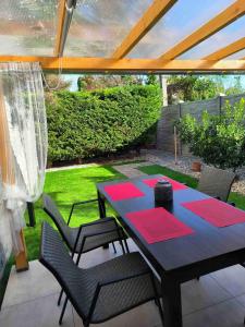 un patio con mesa y sillas con esterillas rojas en Baky House, en Balatonlelle