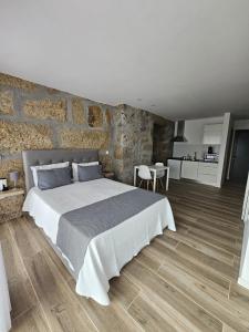 1 dormitorio con 1 cama grande y pared de piedra en Quinta Vilar de Lobos, en Arcos de Valdevez