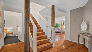 a staircase in a home with white walls and wood floors at Sublime Beach Getaway, Spacious Balcony with BBQ in Copacabana