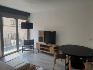 uma sala de estar com uma televisão e uma mesa e cadeiras em Apartament Cèntric a Ribes de Freser Vall de Núria em Ribes de Freser