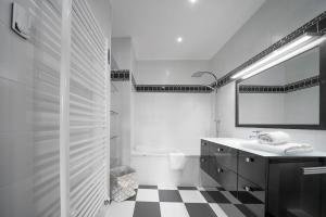 a white bathroom with a black and white checkered floor at L'anthracite - Proche Opéra & Centre-ville in Vichy