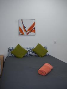 a bed with green pillows and an orange towel on it at aparment la Elipa in Madrid