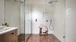 a bathroom with a shower with a pink towel on a chair at Beachfront at Avoca North in North Avoca