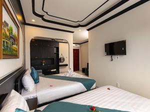 a bedroom with two beds and a flat screen tv at Simon House Hoi An in Hoi An