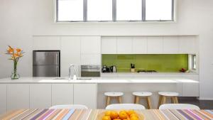 Una cocina con gabinetes blancos y una mesa y sillas. en Killcare Beach Abode with AC, en Killcare 10 fotos más