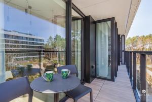 a balcony with a table and chairs and glass walls at Shellter Apartments 117 K - by Jantar Apartamenty in Rogowo