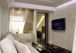 a living room with a couch and a tv on a wall at The Ellinikon - Metro Apartment in Athens