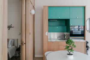 een keuken met groene kasten en een tafel met een plant bij Casa Camisa - Soho - by Frankie Says in Londen