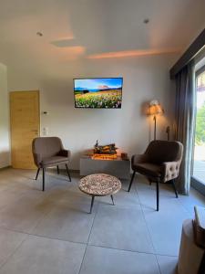a living room with two chairs and a tv on the wall at Les Trois Chaufatons - Chalets Boutiques in Montriond