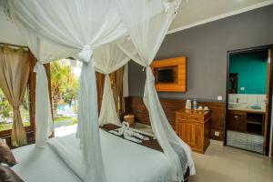 a bedroom with a canopy bed and a bathroom at Tropical Garden by TANIS in Nusa Lembongan