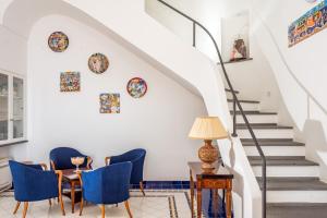 ein Wohnzimmer mit blauen Stühlen, einem Tisch und einer Treppe in der Unterkunft Villa Bijoux - Exclusive pool and sea view in Amalfi