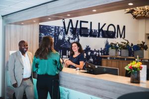 a group of people standing at a reception desk at 50|50 Hotel Belmont in Ede