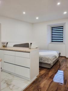 a white bedroom with a bed and a dresser at Stara Pošta Apartment 5 in Grosuplje