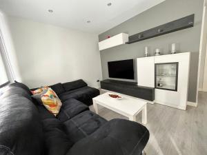 ein Wohnzimmer mit einem schwarzen Sofa und einem Tisch in der Unterkunft Apartamento en pleno centro de Valladolid in Valladolid