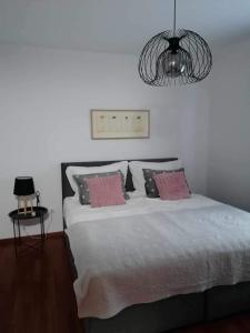 a bedroom with a bed with pink pillows and a chandelier at Apartma Bistrica in Slovenska Bistrica