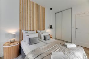 een slaapkamer met een groot bed met witte lakens en kussens bij Aura III Apartments & Free Parking by Downtown Apartments in Gdańsk