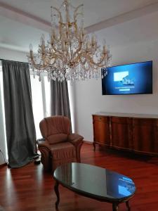ein Wohnzimmer mit einem Kronleuchter, einem Tisch und einem Stuhl in der Unterkunft Apartma Bistrica in Slovenska Bistrica