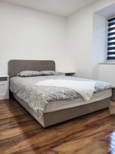 Łóżko w białej sypialni z drewnianą podłogą w obiekcie Stara Pošta Apartment 5 w mieście Grosuplje