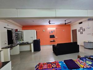 salon z pomarańczowymi ścianami i czarną kanapą w obiekcie The Urban Escape w mieście Udupi